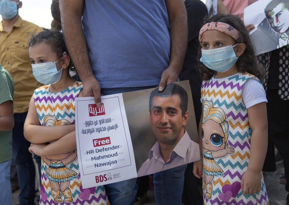 A Palestinian man holds a poster showing Mahmoud Nawajaa, a leading coordinator of the Palestinian-led boycott movement against Israel, BDS, during a protest calling for the EU to press for his release, in front of the German Representative Office, in the West Bank city of Ramallah, Tuesday, Aug. 11, 2020. The activist was arrested on July 30, remains in Israeli custody and has not been charged. Israel says the arrest is not connected to his boycott activities, and that he is is suspected of unspecified “security offenses," but boycott activists accuse Israel of fabricating the case in order to justify the arrest. (AP Photo/Nasser Nasser)