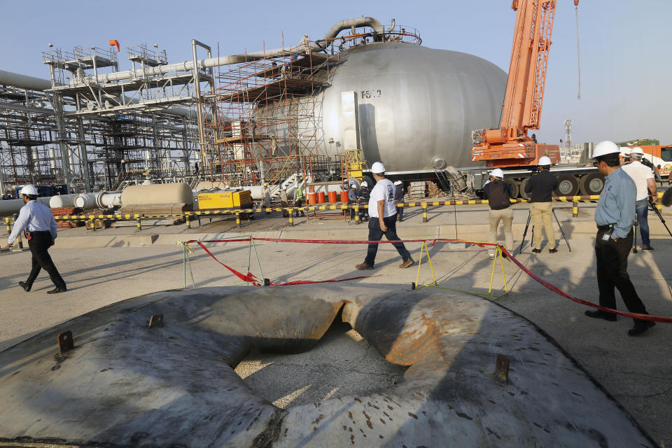 During a trip organized by Saudi information ministry, a hole in a part of a separator is seen on the ground as worker fix the damage in Aramco's oil separator at processing facility after the recent Sept. 14 attack in Abqaiq, near Dammam in the Kingdom's Eastern Province, Friday, Sept. 20, 2019. Saudi Arabia allowed journalists access Friday to the site of a missile-and-drone attack on a facility at the heart of the kingdom's oil industry, an assault that disrupted global energy supplies and further raised tensions between the U.S. and Iran. (AP Photo/Amr Nabil)