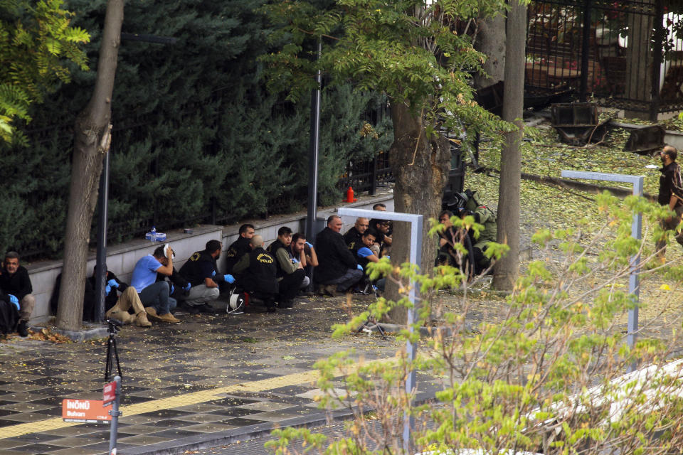 Turkish police officers take cover as bomb disposal experts work in a area after an explosion in Ankara, Sunday, Oct. 1, 2023. A suicide bomber detonated an explosive device in the heart of the Turkish capital, Ankara, on Sunday, hours before parliament was scheduled to reopen after a summer recess. A second assailant was killed in a shootout with police. (AP Photo/Ali Unal)