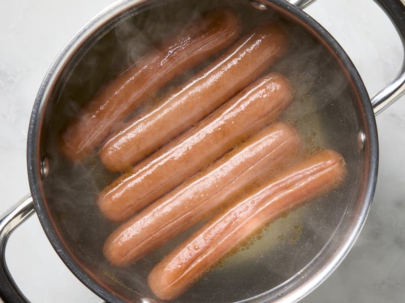 overhead photo of hot dogs cooking in boiling water