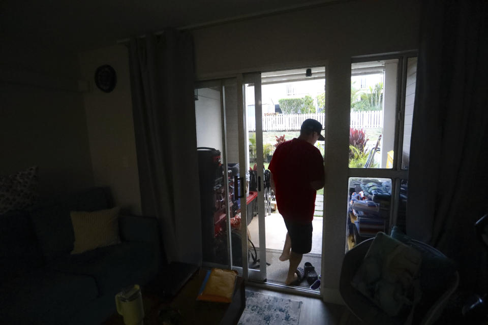 Kawehi Akiona exits his living room to rake his backyard on July 12, 2024, in Wailuku, Hawaii. Akiona and his wife, Tamara, took in her uncle after the Lahaina wildfire burned the family’s home. They are now participants in the nonprofit Council for Native Hawaiian Advancement’s Host Housing Support Program, which offers cash assistance for housing displaced wildfire survivors. (AP Photo/Manuel Valdes)