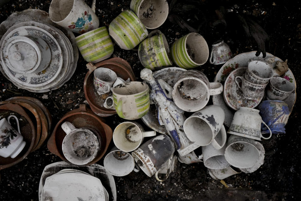 Recovered kitchenware and a statuette lay on the ground after forest fires in Vina del Mar, Chile, Tuesday, Feb. 6, 2024. (AP Photo/Esteban Felix)