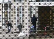 A police officer examines the crime scene next to a covered body following a shooting at the entrance of Building E of the courthouse in Frankfurt January 24, 2014. REUTERS/Ralph Orlowski (GERMANY - Tags: CRIME LAW)