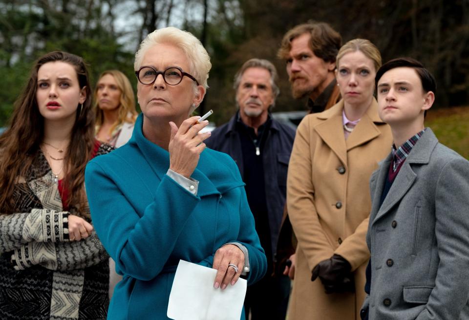 The image shows Jamie Lee Curtis and other cast members from "Knives Out" in a scene where they look serious and concerned outdoors