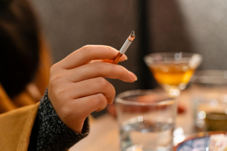 A woman holding a cigarette indoors.