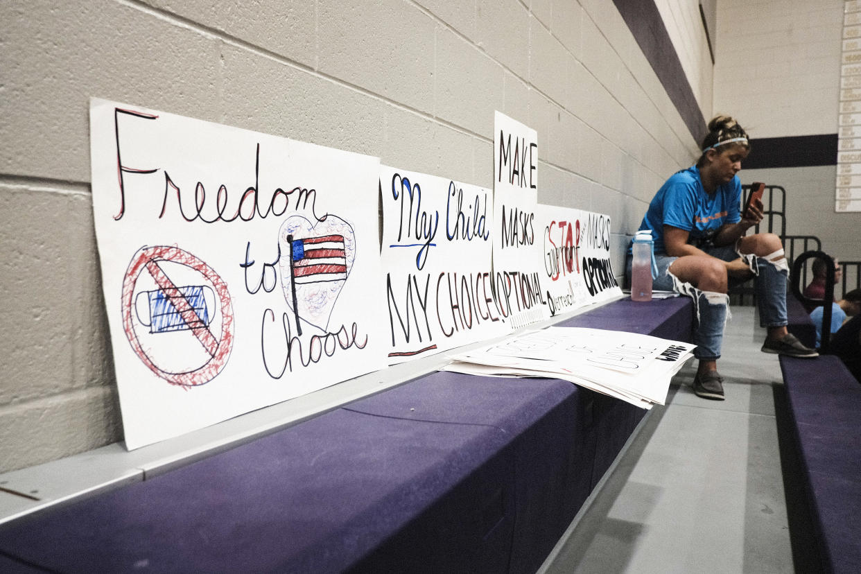 An attendee sits next to anti-vaccine mandate signs at a board of education meeting in Schoolcraft, Mich., in 2021. 