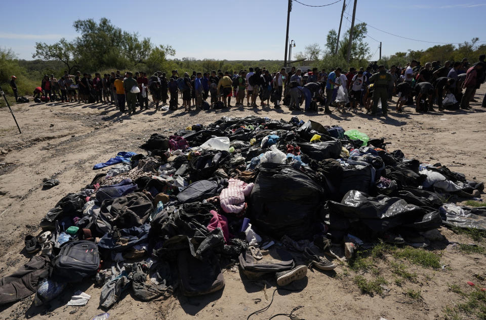 Migrants stands near a pile of discarded items as they wait to be processed by the U.S. Customs and Border Patrol after they crossed the Rio Grande and entered the U.S. from Mexico, Thursday, Oct. 19, 2023, in Eagle Pass, Texas. Starting in March, Texas will give police even broader power to arrest migrants while also allowing local judges to order them out of the U.S. under a new law signed by Republican Gov. Greg Abbott. (AP Photo/Eric Gay)
