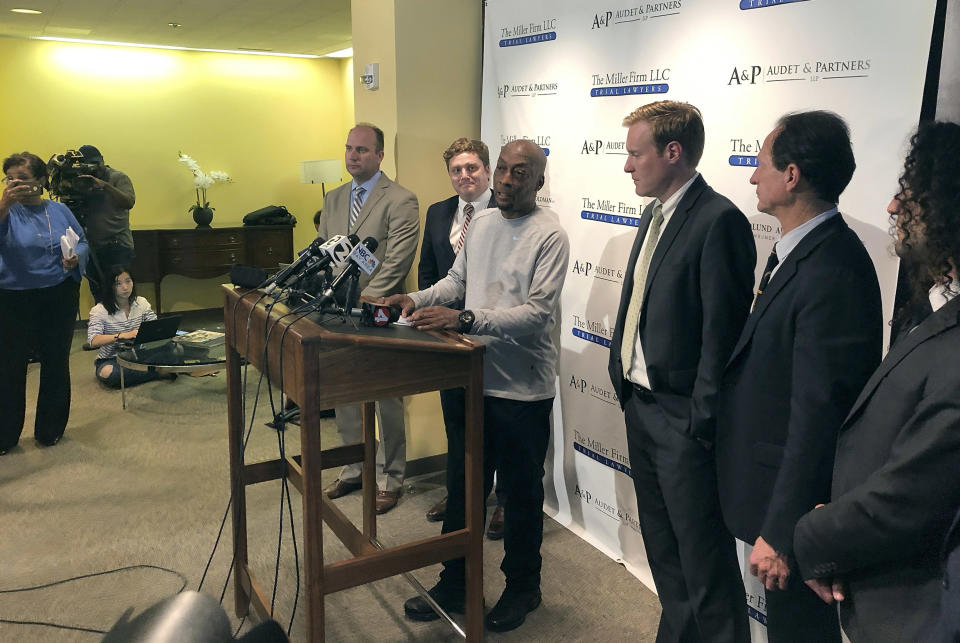 Plaintiff Dewayne Johnson, center at podium, surrounded by his attorneys, takes questions from the media after the Monsanto trial in San Francisco Friday, Aug. 10, 2018. A San Francisco jury ordered agribusiness giant Monsanto to pay $289 million to the former school groundskeeper dying of cancer, saying the company's popular Roundup weed killer contributed to his disease. The lawsuit brought by Johnson was the first to go to trial among hundreds filed in state and federal courts saying Roundup causes non-Hodgkin's lymphoma, which Monsanto denies. (AP Photo/Paul Elias)