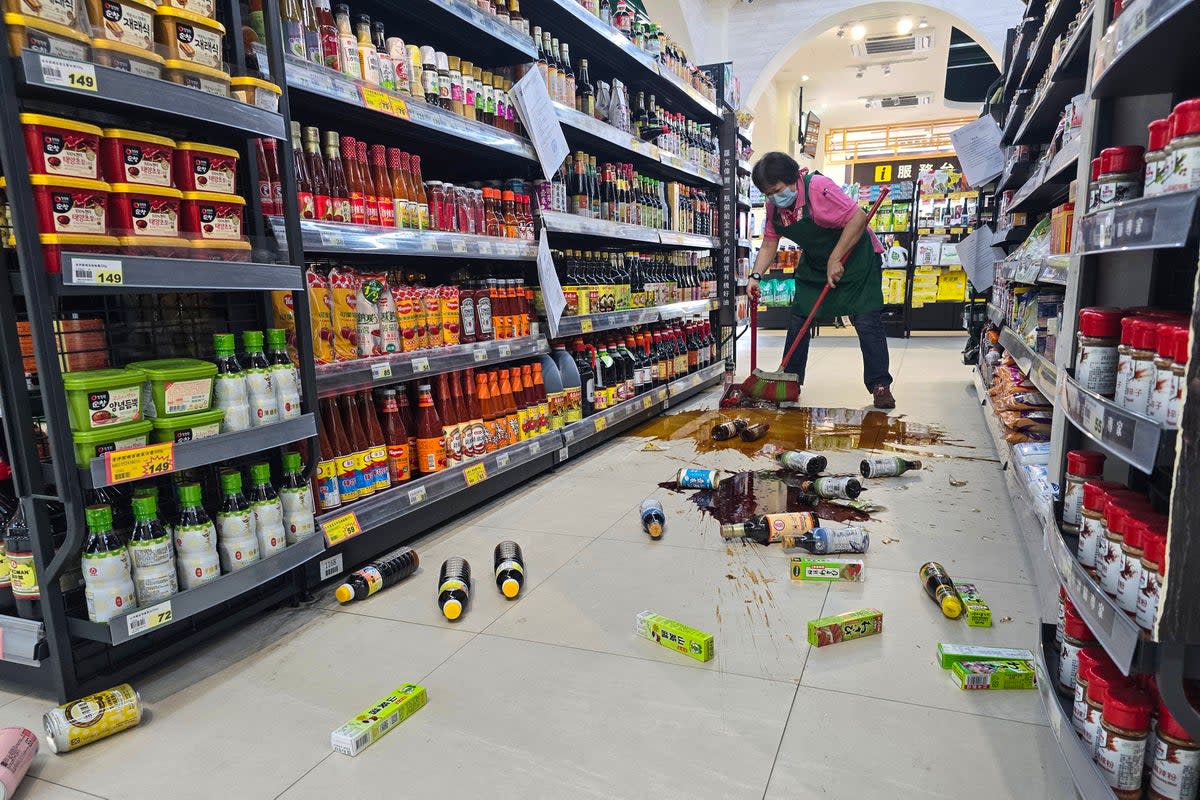 An employee clears broken bottles on the floor of a supermarket in Yilan (CNA/AFP via Getty Images)