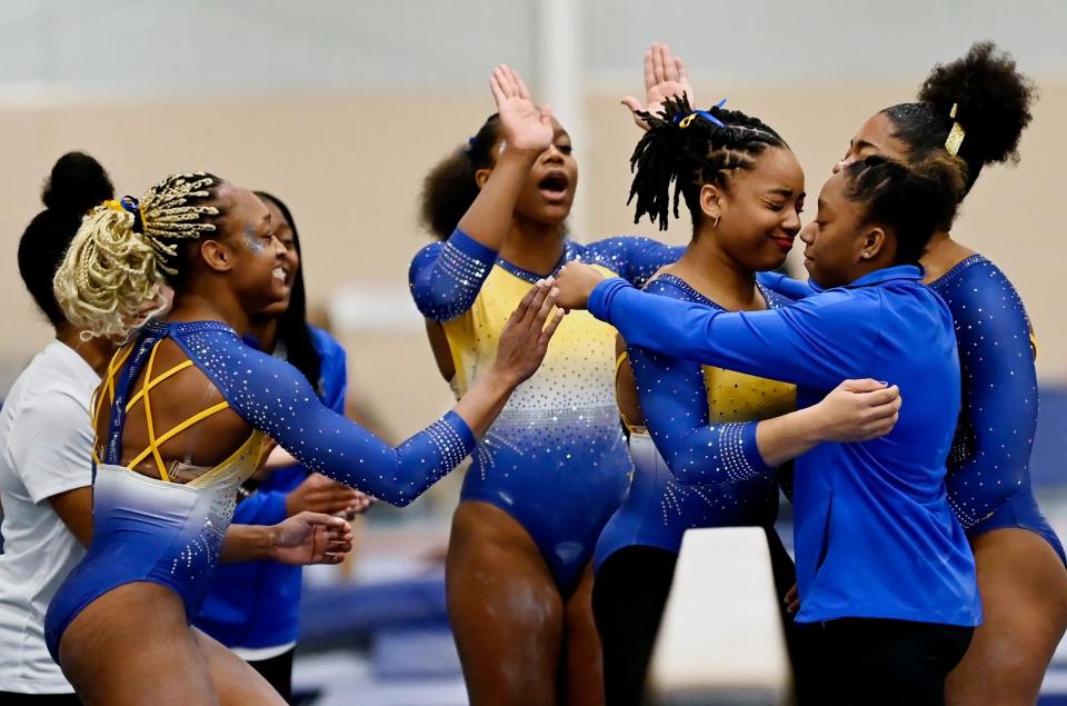 Fisk University gymnast Naimah Muhammad, second from right, reacts after finishing her routine on the balance beam during the Tennessee Collegiate Classic meet Friday, Jan. 20, 2023, in Lebanon, Tenn. Fisk is the first historically Black university to have an intercollegiate women’s gymnastics team.