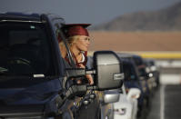 Graduate Maggie Whipple pokes her head out of her truck during a drive-thru graduation for Faith Lutheran High School at the Las Vegas Motor Speedway, Friday, May 22, 2020, in Las Vegas. The school held a special drive-thru graduation amid the coronavirus pandemic. (AP Photo/John Locher)