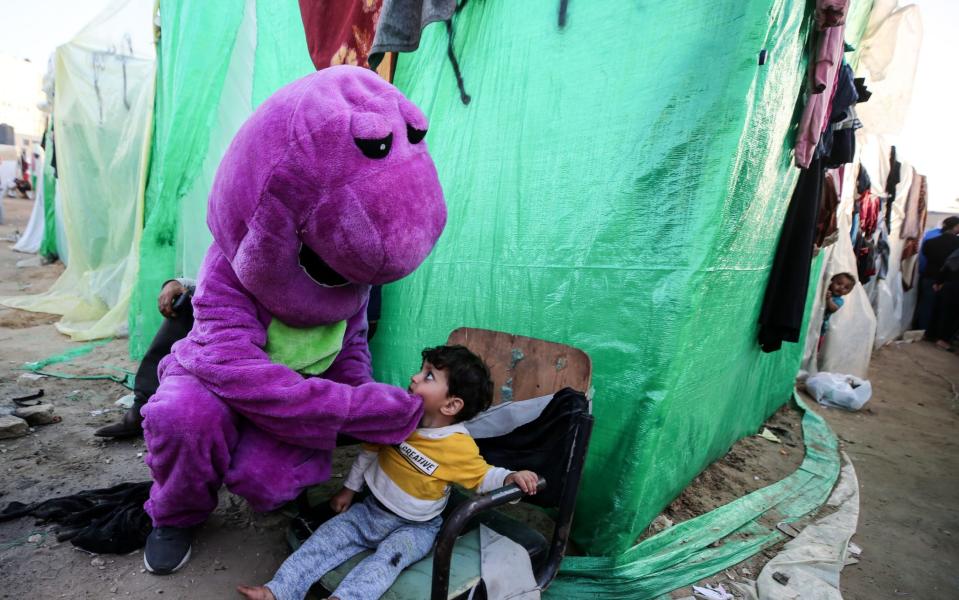 A Palestinian clown interacting with children who have fled their homes due to Israeli strikes