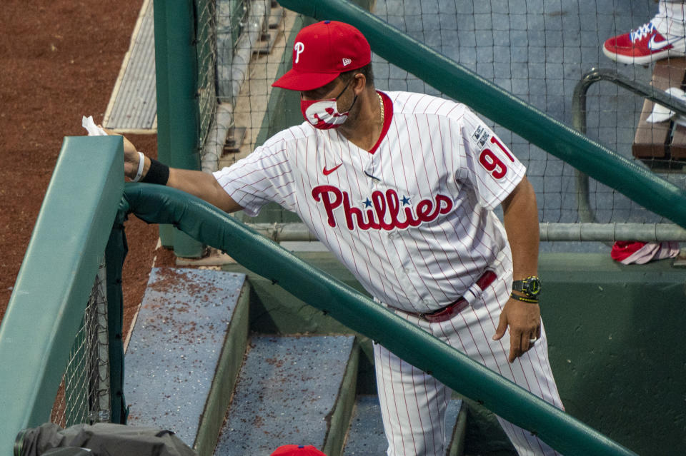 Philadelphia Phillies Infield Coordinator Juan Castro wipes down the railing during the first inning of a baseball game against the Miami Marlins, Friday, July 24, 2020, in Philadelphia. (AP Photo/Chris Szagola)