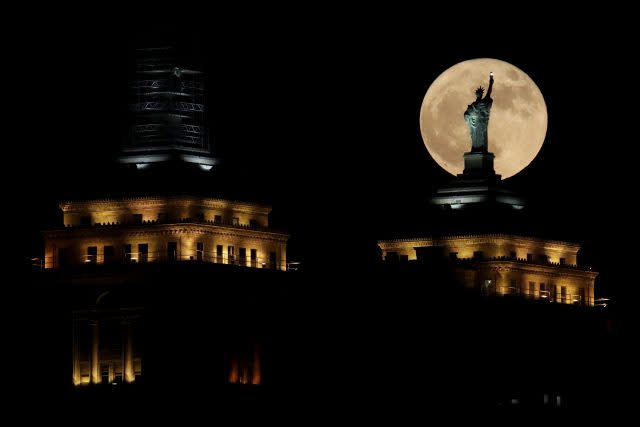 A supermoon rises in front of a replica of the Statue of Liberty sitting atop the Liberty Building in Buffalo, New York state (Julio Cortez/AP)