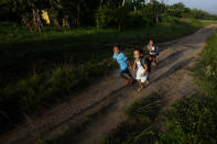 Indigenous Tembe boys run to school at the Tenetehar Wa Tembe village in the Alto Rio Guama Indigenous territory, in Paragominas municipality, in Para state, Brazil, Tuesday, May 30, 2023. (AP Photo/Eraldo Peres)