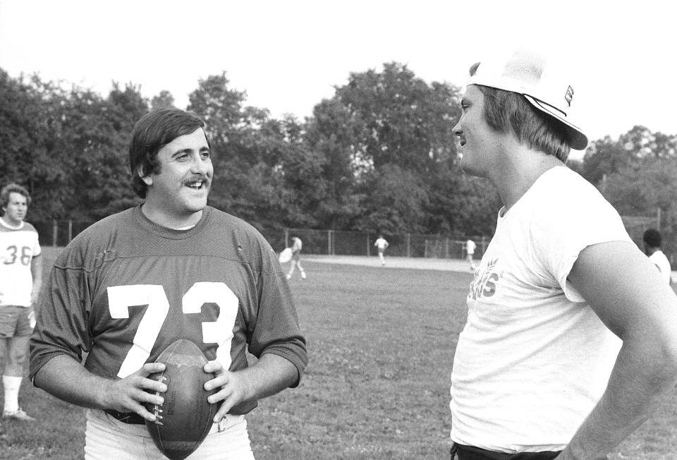 Carmen Pizzuto, of Saddle Brook, N.J, left, and Chris Olsen of Garfield, take a break from practice with members of the Boonton Bears semipro football team at the field in Boonton, N.J., on July 20, 1976.