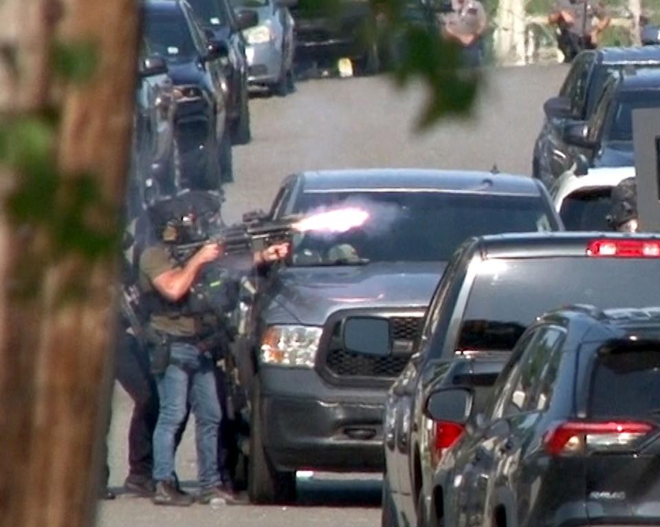 A SWAT officer shoots a cannister into the Ravenwood Drive home Friday afternoon where Maxwell Johnston had kept them at bay. Johnston is the suspect in the slaying of Gabriella Caroleo in Manchester.