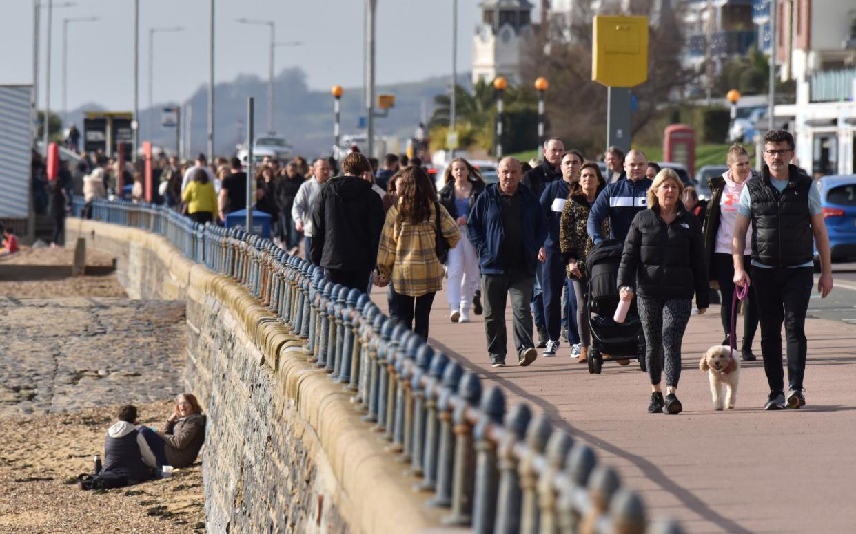 People walk beside the beach on a warm sunny day as the weather warms for the week ahead on February 21, 2021 in Southend,