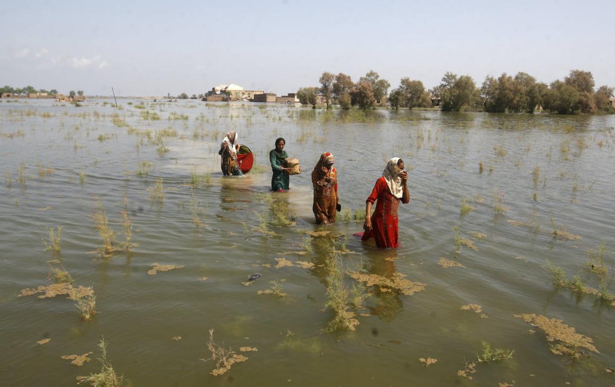 Pakistani women wade through floodwaters as they take refuge on Sep. 2, 2022. (AP Photo/Fareed Khan)