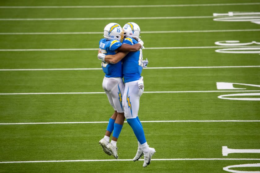 INGLEWOOD, CA - OCTOBER 25: Chargers quarterback Justin Herbert, right, celebrates with wide receiver Jalen Guyton after he caught Herbert's 70-yard touchdown pass in the third quarter against the Jaguars at an empty SoFi Stadium on Sunday, Oct. 25, 2020 in Inglewood, CA. The rookie quarterback finished 27 of 43 for 347 yards and three touchdowns. He also led the Chargers in rushing with 66 yards on nine carries and scored a touchdown on the ground. Herbert's 66 yards set a franchise record for rushing yards by a quarterback. (Allen J. Schaben / Los Angeles Times)