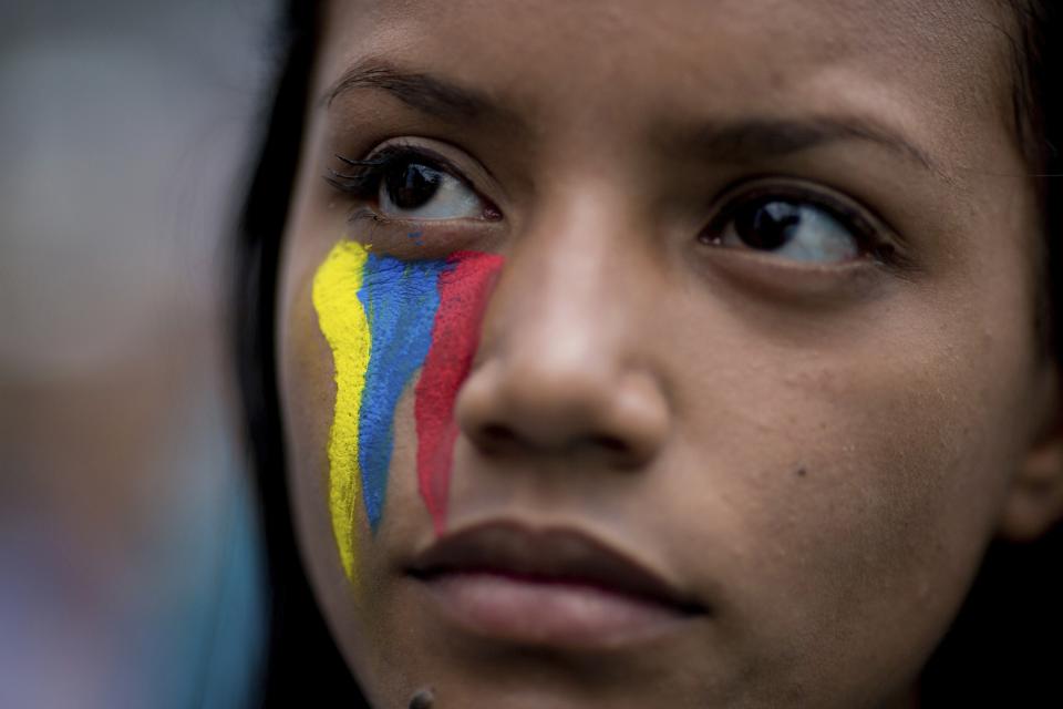 FILE - A demonstrator wearing painted stripes that represent Venezuela's national flag attends a rally with humans rights activist in Caracas, Venezuela, Friday, Feb. 28, 2014. Ten years after Chavez's death, Venezuelans find themselves in a country that has largely fallen apart, as lavish government spending made possible by a historic oil boom ended and economic liberalization measures have deepen inequality. (AP Photo/Rodrigo Abd, File)