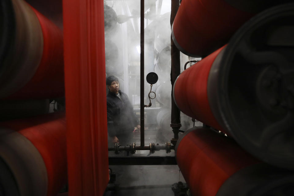 In this Jan. 1, 2019, photo, a worker monitors rolls of fabric at a dyeing factory in Hangzhou in east China's Zhejiang province. China's slowing economy is squeezing the urban workers and entrepreneurs the ruling Communist Party is counting on to help transform this country from a low-wage factory floor into a prosperous consumer market. (Chinatopix via AP)