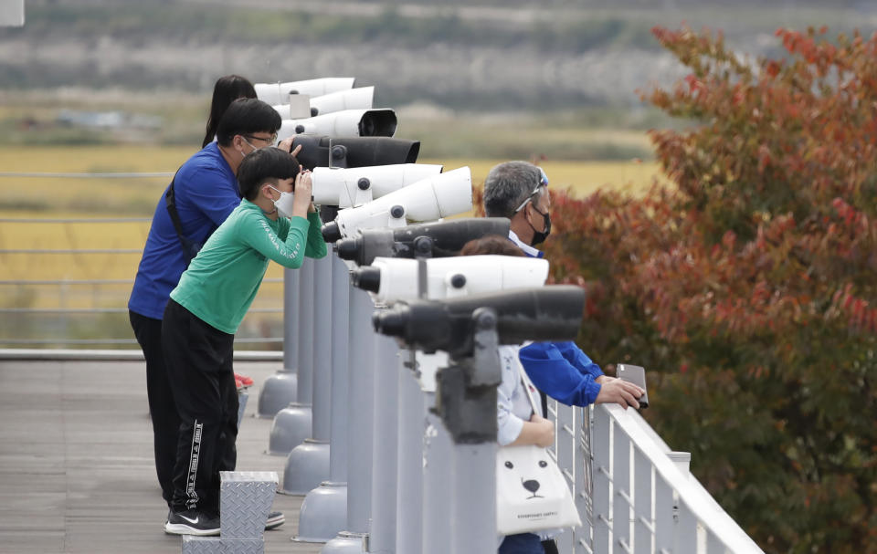 Visitors wearing face masks use binoculars to view from the Imjingak Pavilion in Paju, South Korea, Sunday, Oct. 11, 2020. North Korean leader Kim Jong Un warned that his country would "fully mobilize" its nuclear force if threatened as he took center stage at a military parade that unveiled what appeared to be a new intercontinental ballistic missile and other weapons Saturday. (AP Photo/Lee Jin-man)