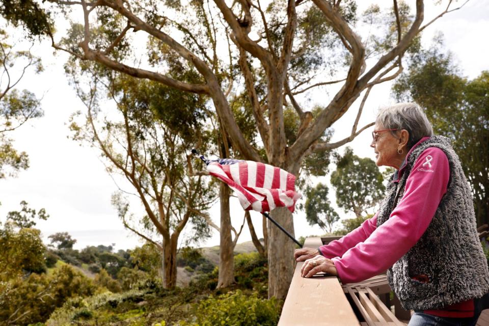 Sallie Reeves looks out at the view from her back deck at trees and grass.