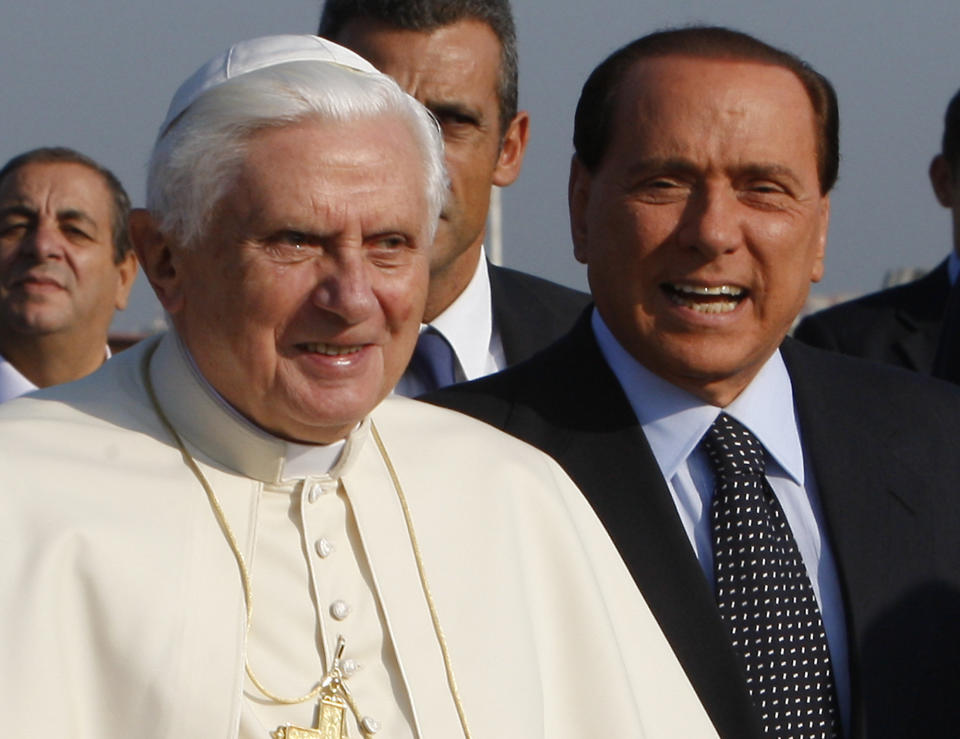 FILE - In this Saturday, Sept. 26, 2009 file photo Pope Benedict XVI is escorted by Italian Premier Silvio Berlusconi, right, as he leaves for his pastoral trip to the Czech Republic from Ciampino Military airport, near Rome. Berlusconi, the boastful billionaire media mogul who was Italy's longest-serving premier despite scandals over his sex-fueled parties and allegations of corruption, died, according to Italian media. He was 86. (AP Photo/Alessandra Tarantino, File)