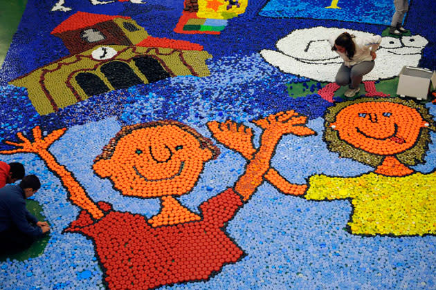 Schoolchildren put bottle caps on the floor to make a mosaic at a school in the northern Asturias village of Ujo, April 26, 2012. Children, teachers and parents of a school have collected more than 150000 caps that will be sold to help an Asturian physically disabled girl. REUTERS/Eloy Alonso