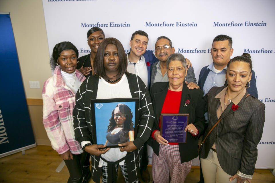 Bridgette Newton holds a picture of her late daughter Brittany Newton next to Miriam Nieves, holding a plaque, who received Brittany Newton's heart in a transplant at Montefiore Moses Hospital in the Bronx borough of New York, on Tuesday, Nov. 22, 2022.Their families stand with them. Doctors at the hospital say the transplant, performed in April, is the first time a heart from an HIV-positive donor was successfully transplanted into an HIV-positive recipient. (AP Photo/Ted Shaffrey)