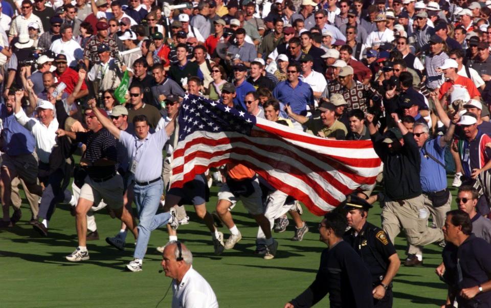 Fans storm the 18th fairway following the last twosome at the 33rd Ryder Cup Matches in Brookline, MA on Sept. 26, 1999. The US team prematurely celebrated their win after Justin Leonard made a 45-foot hole on 17 - GETTY IMAGES