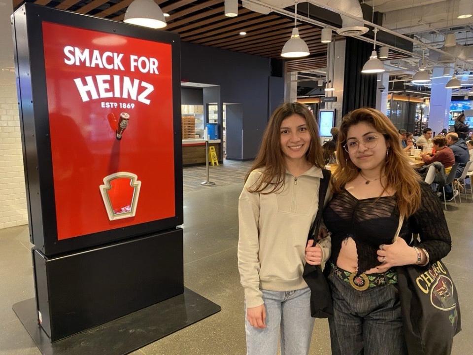Mari Zavala, right, shows her cousin, Yunuen Medina, around Navy Pier in Chicago, where the pair came across an unusual sight, a dispenser meant to tempt locals into adding ketchup to hot dogs.