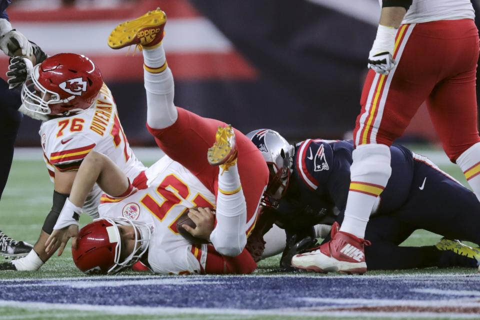 FILE - In this Sunday, Dec. 8, 2019, file photo, Kansas City Chiefs quarterback Patrick Mahomes lands on the turf after he was sacked by New England Patriots defensive tackle Adam Butler, right rear, in the first half of an NFL football game in Foxborough, Mass. In three previous meetings with Kansas City's Patrick Mahomes, the Patriots defense has had its most success when it's been able to force turnovers and get pressure on him. But that's easier said than done against a quarterback who has yet commit a turnover this season and is completing a career-high 68% of his passes.(AP Photo/Charles Krupa, File)