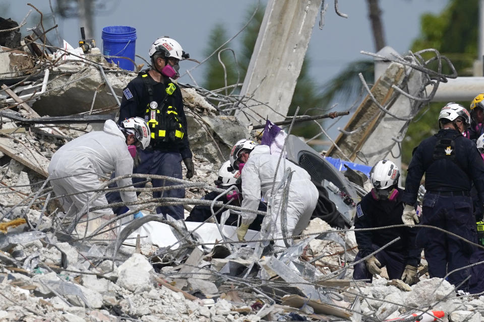 Rescue workers handle a tarp containing recovered remains at the site of the collapsed Champlain Towers South condo building on Monday. Source: AP