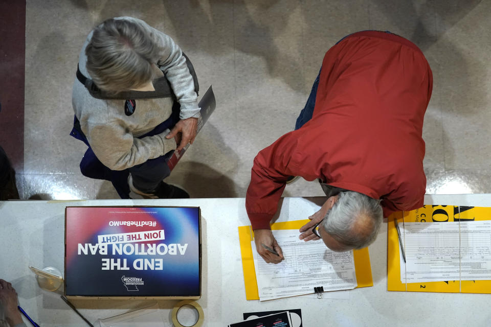 FILE - A residents places his signature on a petition during Missourians for Constitutionals Freedom kick-off petition drive, Feb. 6, 2024 in Kansas City, Mo. Abortion rights advocates are trying to get initiatives to protect reproductive on the ballot in several states this year, and one major difference has emerged in their proposed language — whether to include mental health as an exception. (AP Photo/Ed Zurga, File)