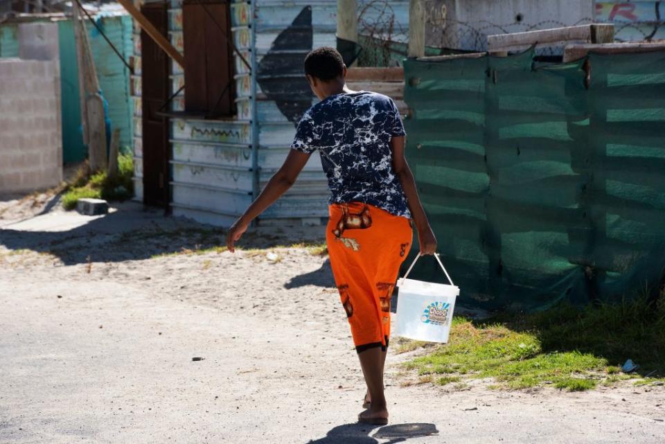 A woman carries a bucket of water which she filled at a nearby tap in Zwelitsha, an informal settlement in Khayelitsha that is home to millions of people in mostly impoverished circumstances, near Cape Town on February 24, 2022.<span class="copyright">Rodger Bosch—AFP/Getty Images</span>
