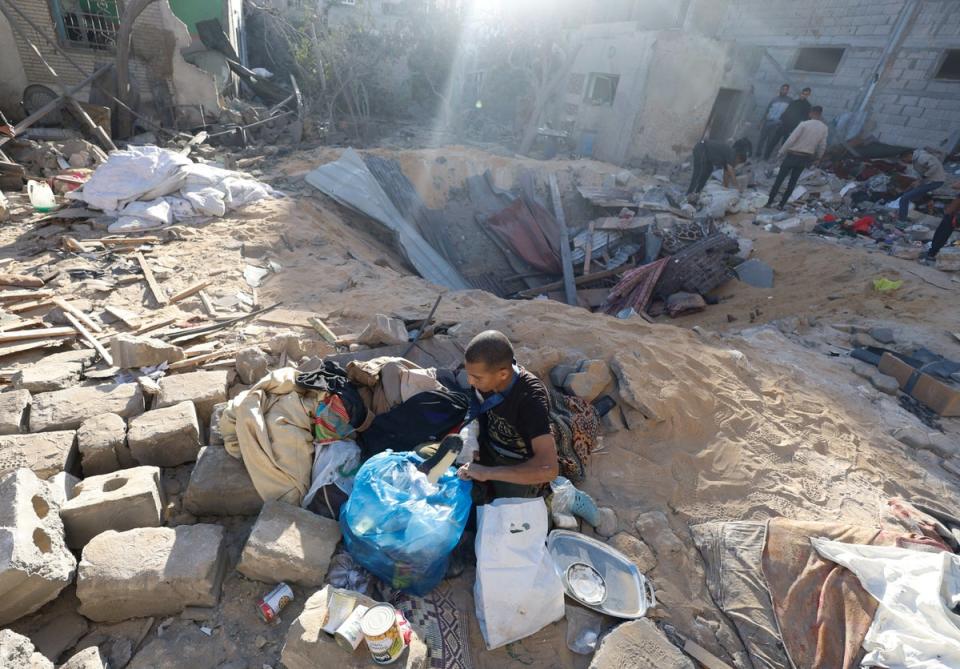 A Palestinian man gathers his belongings after an Israeli airstrike on a house in Rafah (Reuters)
