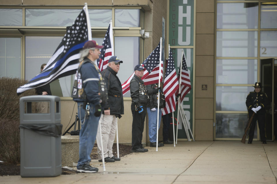 A column of men holding flags greet people as they arrive before funeral services for slain McHenry County Sheriff's Deputy Jacob Keltner on Wednesday, March 13, 2019, at Woodstock North High School in Woodstock Ill. Keltner was shot and killed while trying to serve an arrest warrant at a hotel on March 7, 2019. (Scott P. Yates/Rockford Register Star via AP)