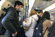 A traveller wears a mask on a busy tube in London, Monday, March 16, 2020. For most people, the new coronavirus causes only mild or moderate symptoms, such as fever and cough. For some, especially older adults and people with existing health problems, it can cause more severe illness, including pneumonia. (AP Photo/Kirsty Wigglesworth)