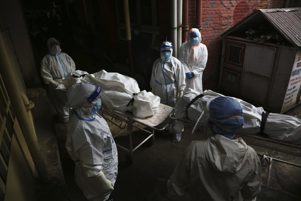 Paramedics get ready to load dead bodies of COVID-19 victims onto an ambulance for cremation at a government run hospital in Kathmandu, Nepal, Wednesday, May 12, 2021. Political turmoil has returned to Nepal, which has had eight different governments in a decade and is experiencing its worst COVID-19 surge with acute shortages of health facilities and oxygen for patients.(AP Photo/Niranjan Shrestha)