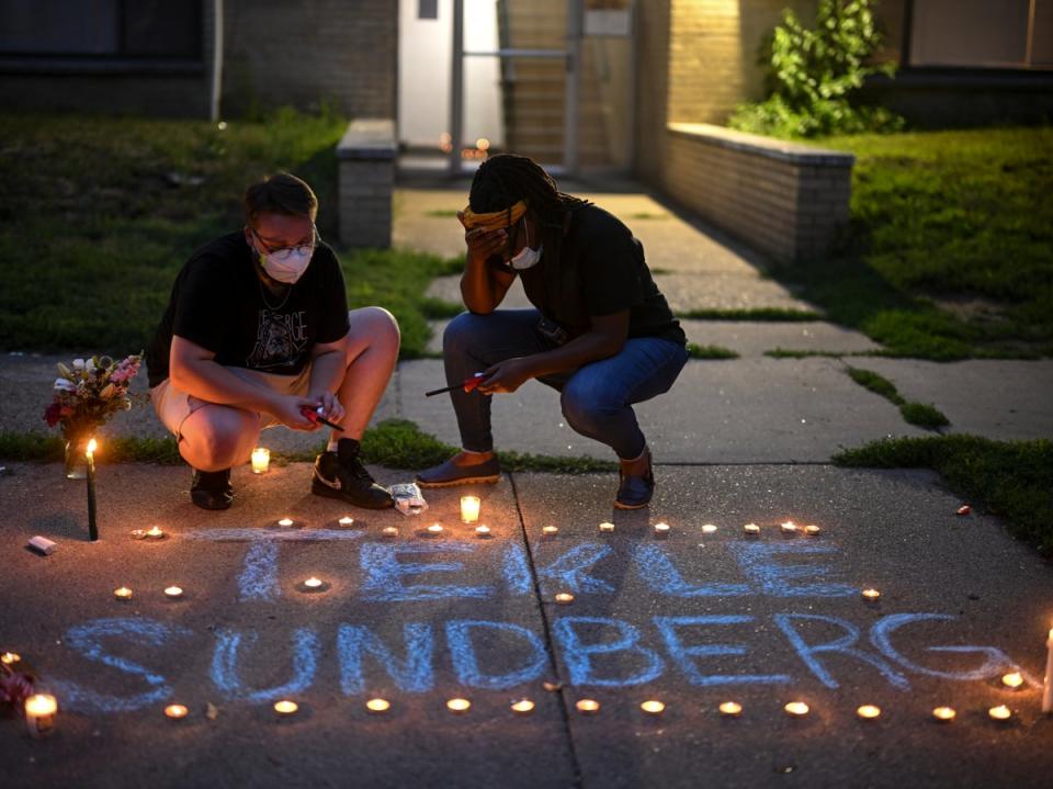 Marcia Howard, activist and George Floyd Square caretaker, right, takes a moment as she lights candles during a vigil for 20-year old Andrew Tekle Sundberg Thursday, July 14, 2022 outside the apartment building where he was killed (AP)
