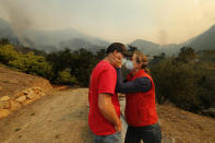 <p>Dan Bellaart and his wife Mary McEwen comfort each other in the back yard of their home that includes an avocado ranch on 9 acres of land on Toro Canyon Rd. as the Thomas fire burns in the background on Dec., 11, 2017 in Montecito, Calif. They have lived here since 2002. (Photo: Mel Melcon/Los Angeles Times via Getty Images) </p>