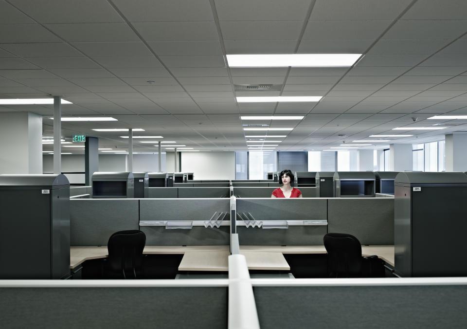 Businesswoman standing alone at cubicle in empty office