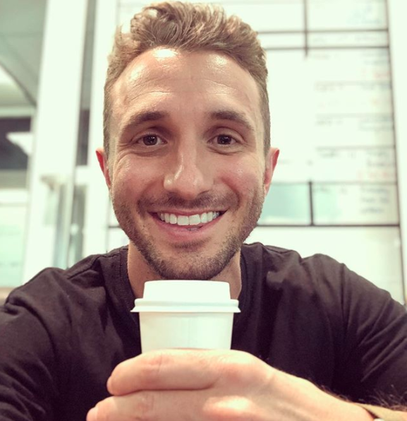 Tommy Little smiling while holding a coffee cup