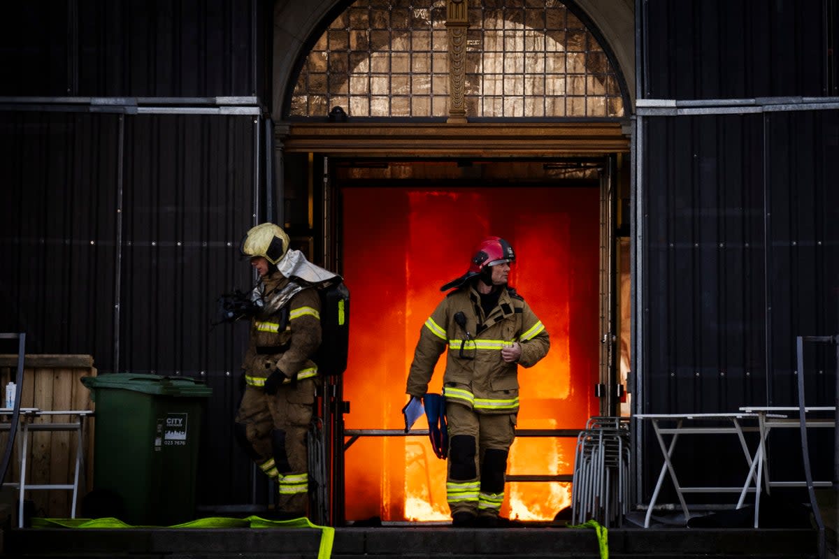 Firefighters exit the burning innards of the building (Getty)