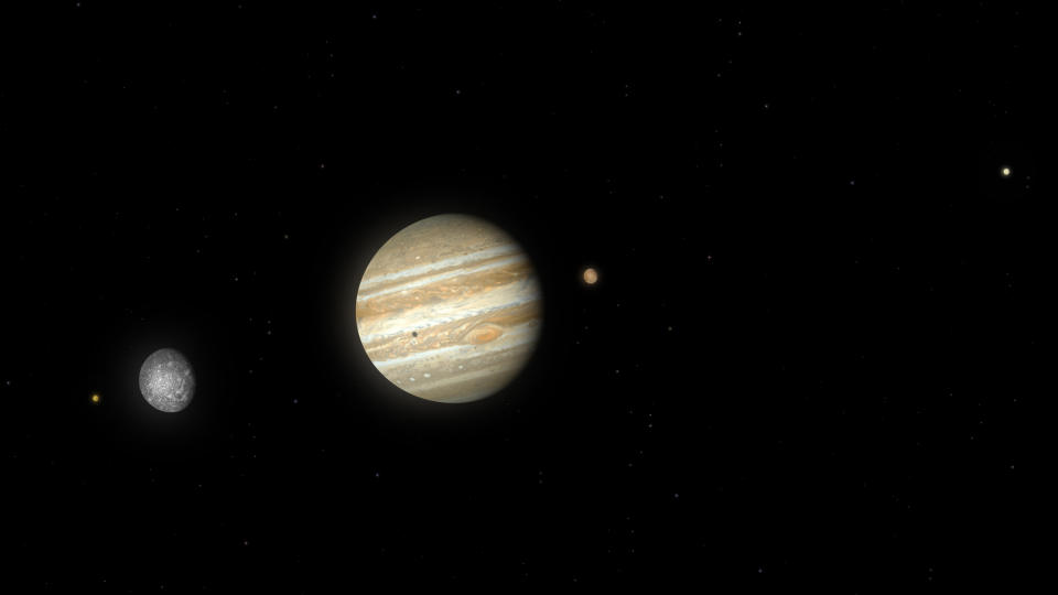  A large gas giant hangs left of center surrounded by smaller moons. 