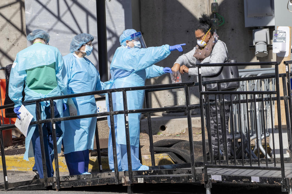 Image: A member of the Brooklyn Hospital Center helps a person who was just tested for COVID-19 put an object in a biohazard bag, Thursday, March 26, 2020, in New York. (Mary Altaffer / AP)