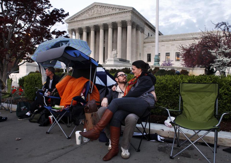 Monica Haymond, right, sits with her boyfriend Dana Stuster, both recent transplants to Washington from Pasadena, Calif., as they wait in line for tickets to the Supreme Court on the eve of the Supreme Court arguments on President Obama's health care legislation, in Washington, on Sunday, March 25, 2012. "We're going to wait to enter until Tuesday," says Haymond, a legal assistant who has been in line since Friday, "since that's when they'll discuss the individual mandate. They'll be talking about unprecedented things, it's going to be historic." (AP Photo/Jacquelyn Martin)