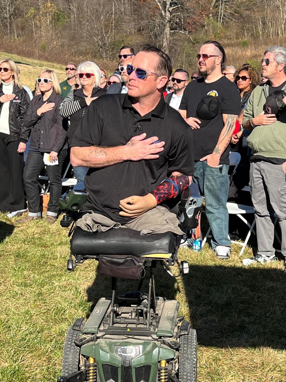 Retired Army Sgt. Bryan Anderson, a triple amputee, puts his hand over his heart during the singing of the national anthem Nov. 9, 2022, in Cumberland Furnace, Tenn., at the dedication of his new, free customized home built by the Gary Sinise Foundation